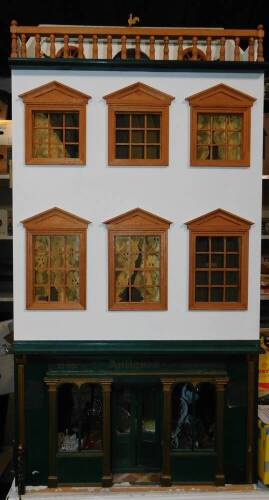 A three storey dolls house, modelled as an antique shop, with furniture and contents, 98cm H, 45cm W, 38cm D.