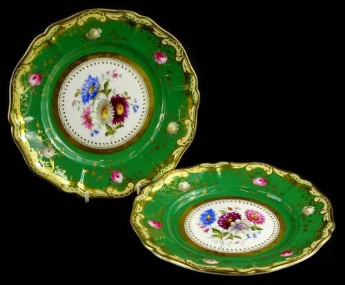 A pair of early 20thC Royal Worcester porcelain plates, each painted with flowers within green and yellow borders, picked out in gilt, circa 1909, 22cm dia.