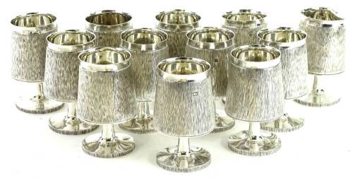 A set of twelve Elizabeth II silver goblets, each with a tapering form with a textured finish and circular foot, Birmingham 1970, by C.J Vander Limited, some pieces (AF), 106¾oz.