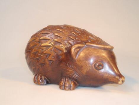 A brown glazed pottery hedgehog money box with incised decoration