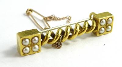 A Victorian bloomed gold brooch, with twist design bar centre and two square ends, each set with seed pearls, with additional safety chain and later pin back, 4.5cm wide, 5.1g all in, in John Purser & Sons box.