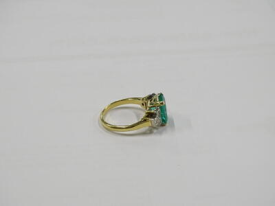 An emerald and diamond ring, with central rectangular cut emerald, in yellow gold claw setting, approx 2.51cts, with round brilliant cut diamond shoulders, three to each side, ring size M, 5.3g all in. - 2