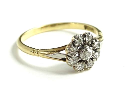 An 18ct gold diamond cluster ring, of small proportion with eight stone border and single stone to centre, with splayed shoulders on bi-colour metal and etched shoulders, ring size N½, 2.3g all in.