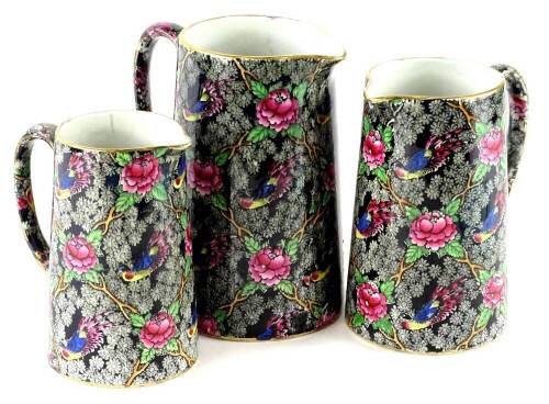 A graduated set of three late 19th/early 20thC transfer printed and hand painted jugs, each decorated with flowers, birds and leaves, the largest 19.5cm H.