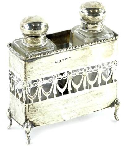 An early 20thC pierced silver scent bottle holder, containing two rectangular glass scent bottles with stoppers, on shaped feet, marks indistinct.