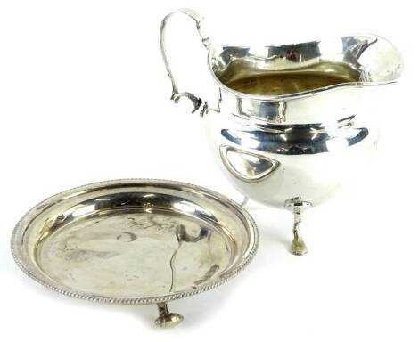 A small silver waiter or pin tray, with beaded border, on three scroll cast feet and a silver cream jug, 5oz.