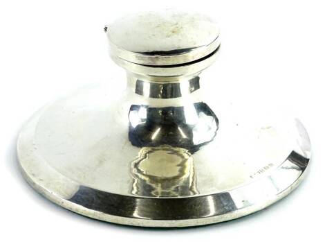 A George VI silver mounted capstan inkwell, with loaded base, the hinged lid enclosing a blue glass insert, Birmingham 1946, 14cm dia.