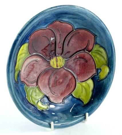 A Moorcroft pottery shallow dish, decorated centrally with a deep red flower, on a navy ground, 19cm dia.