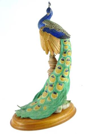 A Franklin Mint bisque porcelain figurine, The Royal Peacock, made for the Royal Society for the Protection of Birds, with hardwood stand.