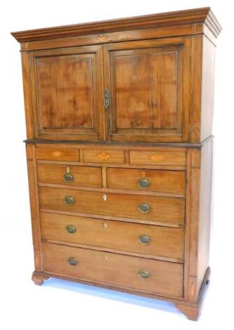 A 19thC clothes press, the top with a moulded cornice, above two panelled doors, the base with three concealed drawers above two short, three long drawers, each with oval brass handles, on ogee bracket feet, adapted, 191cm H, 130cm W.