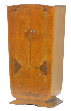 An Art Deco figured walnut small wardrobe, with two doors, above two drawers on a shaped base, 86cm W.