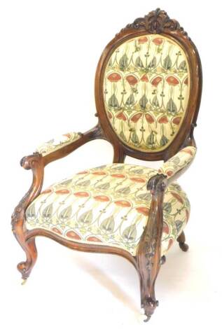 A 19thC mahogany spoonback open armchair, with a buttoned back, padded arms and seat, decorated in Arts and Crafts fabric, on cabriole legs.