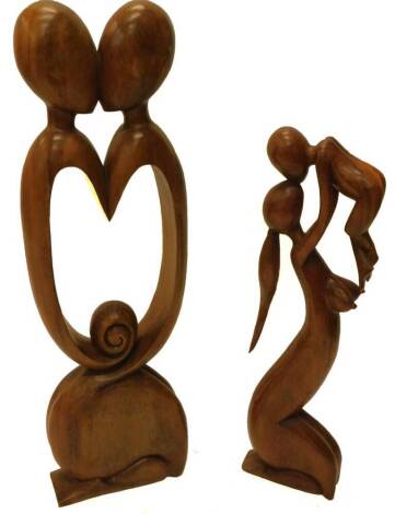 Two hardwood carvings one modelled in the form of two intertwined figures, with central pierced heart motif, 97cm H, and a nude of a mother and child, 78cm H.