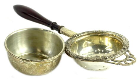 A silver tea strainer, with turned wood handle and Celtic band and stand, Birmingham 1971.