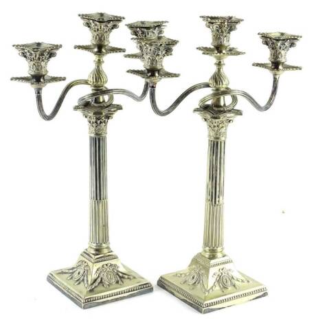 A pair of three branch candelabra, each sconce with gadrooned borders, on a Corinthian column and square base cast with roundel's, swags etc., 45cm H, 30cm W.