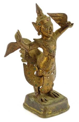 An Indian figure of a god, in standing pose, dress picked out with green stones, on a shaped base, 19cm H.