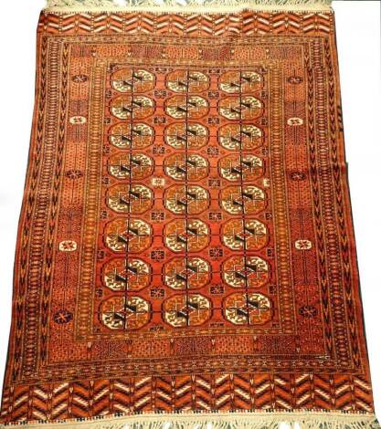 A Turkaman type rug, with a design of three rows of medallions on a red ground with multiple borders, 165cm x 125cm.