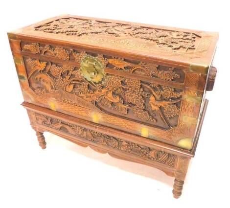 An Eastern carved camphor chest, decorated with prunus, birds etc., on a stand with a frieze drawer on turned legs, 103cm W.