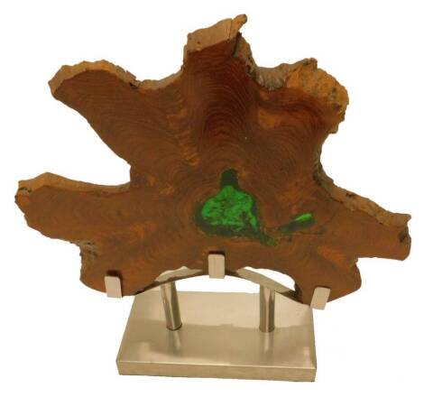 An abstract wood sculpture, made from a slice of a trunk, inset to centre with green crackled perspex on an aluminium base, 71cm W.