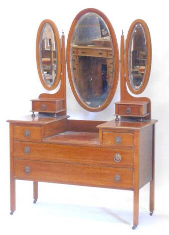 An Edwardian mahogany and boxwood strung dressing table, with three oval mirrors, two trinket drawers and a stepped base with two short and two long drawers on castors, 113cm W.