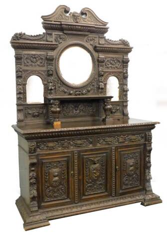 A late Victorian ebonised oak sideboard, the raised back with a central circular bevelled mirror plate flanked by two arched bevelled mirror plates, profusely carved with fruit, leaves, masks etc., the base with an arrangement of two frieze drawers above 