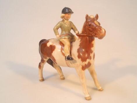 A Beswick model of a girl on a skewbald pony wearing a green jacket