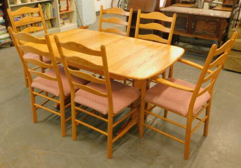 An Ercol light elm extending dining table, the rectangular top with moulded edge on end supports, the top 88cm x 151cm, and a set of six ladderback chairs, each with a padded seat two with arms.