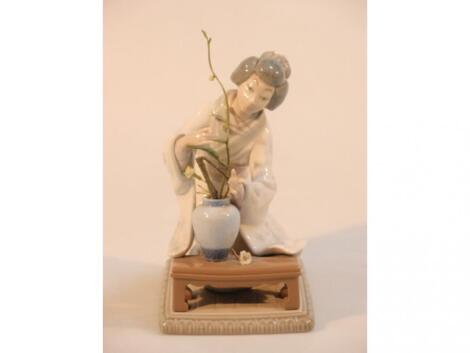 A Lladro figure of a young Japanese woman arranging flowers on an oblong base