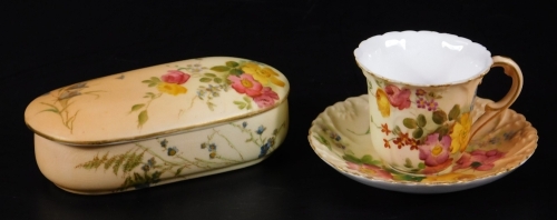 A Royal Worcester blush ivory hair grip box and cover, puce factor mark, c1913, 10cm L, together with a blush ivory miniature cup and saucer, green factory mark, saucer 8cm Dia. (2)