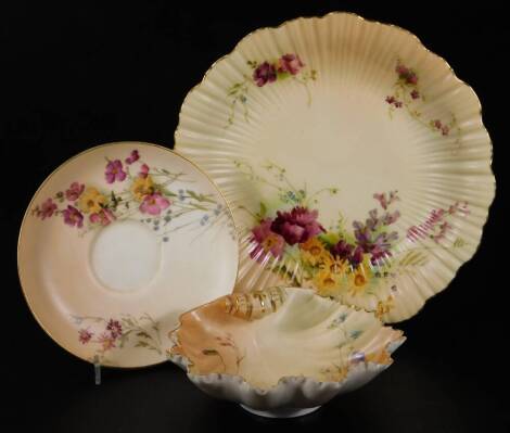 A Royal Worcester blush ivory shell shaped tray, shape code 1413, puce factory mark, c1900, 14cm Dia. together with a fluted plate, shape code 1416, Worcester factory mark, c1914, 21cm Dia. and a blush ivory saucer, puce factory mark, c1915, 14cm Dia. (3