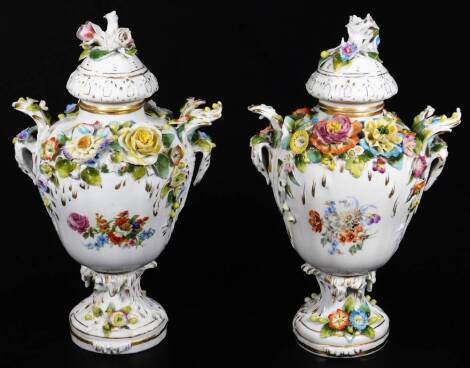 A pair of 19thC Potschappel porcelain vases, in the manner of Carl Thieme each heavily encrusted with flowerheads, polychrome decorated predominately in green, yellow and blue, on circular gilt lined feet, blue crown and N marks beneath, 28cm H. (2)