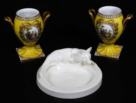 An undecorated Creamware dish, with fox to the surround, unmarked, 11cm Dia. and a pair of Meissen style Helena Wolfsohn design vases, of urn form on inverted stems and gilt lined square bases, decorated with panels of figures, cross sword mark beneath. 