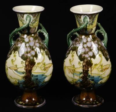 WITHDRAWN BY VENDOR PRESALE A pair of early 20thC Secessionist pottery vases, of shouldered circular form, with entwined bark handles, on oval feet, each decorated with scenery, predominately in green and purple, unmarked, each numbered 3320D, 27cm H. (2