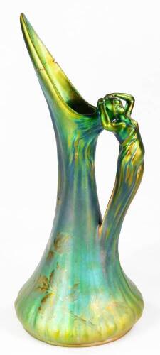 An early 20thC Jerome Massier Art Nouveau pottery jug, in green with figure handle wearing flowing robes, the inverted ribbed body decorated with gilt flowers, signed and marked beneath, 47cm H. (AF)