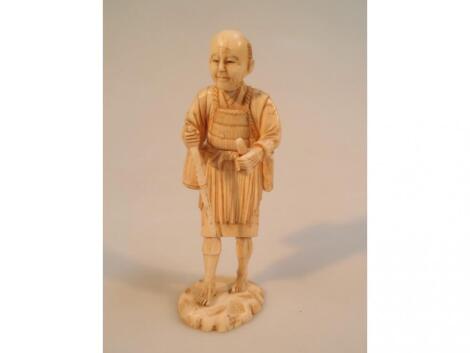 A Japanese carved ivory standing figure of a man with work attire and tools