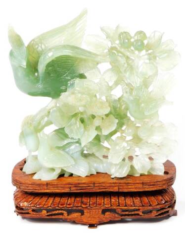 A 20thC jade style carving of a bird, in naturalistic setting, on removable wooden plinth base, heavily carved with a gadrooned border, unmarked, 22cm H.