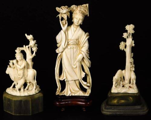 A late Meiji period ivory figure, of a standing Geisha in flowing robes holding floral staff, on a wooden base, 16cm H and two further ivory carvings. (3)