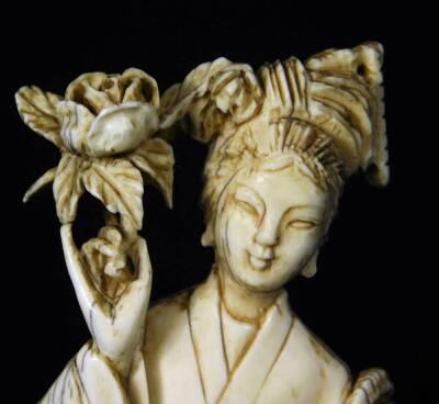 A late Meiji period ivory figure, of a standing Geisha in flowing robes holding floral staff, on a wooden base, 16cm H and two further ivory carvings. (3) - 6