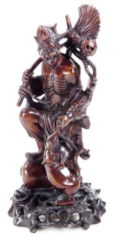 A heavily carved Chinese root carving, of a figure in flowing robes holding staff aside dog, on a removable ebonised plinth base, 38cm H.