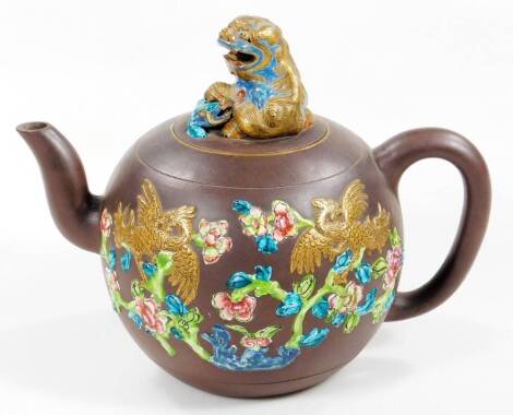 A Chinese red ware pottery punch pot, of circular form with gilt highlights, elaborate dog of fo lid and plain handle and spout, the main body raised with flowers and scrolls, in green, pink and blue with gilt highlights, unmarked, 28cm H.