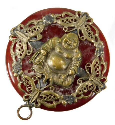 An early 20thC Chinese pendant, on a polished stone ground, raised with a figure of Buddha, surrounded by pierced flowers and scrolls, with a plain ring top, 5cm H.