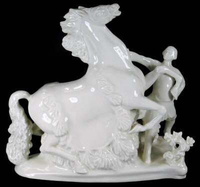 A Russian Verbilki white porcelain figure group of a rearing horse and master, on a floral ground, red stamped mark beneath, 27cm H.