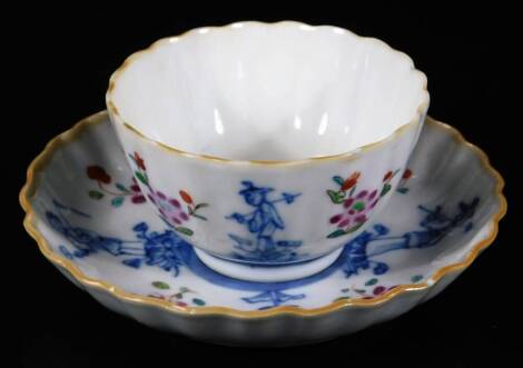 A 18thC Chinese fluted tea bowl and saucer, decorated with under glaze blue figures and flowers with polychrome flowers below a yellow rim.