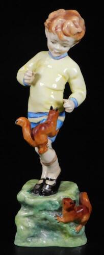 A Royal Worcester figure, representing October's child, wearing a yellow pullover and blue shorts with red squirrels, no. 3417, by F.C. Doughty, black marked, 19cm H.