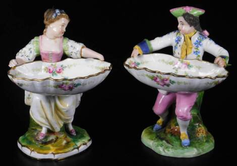 A pair of Minton's sweet meat or salt figures, c1900, in the form of a boy and girl holding a shell decorated with floral swags, 19cm H.