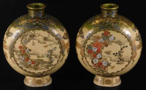 A pair of Japanese late Meiji period pottery Satsuma moon flasks, each of circular form, decorated with butterflies and flowers, with gilt highlights and oval feet, each marked beneath, 23cm H. (2)