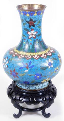 A Chien Luns Chinese cloisonné vase, the bellied circular body with trumpet stem profusely decorated with flowers, predominately, in yellow, white, brown and blue, on a light blue ground, on circular foot, with associated ebonised stand, the vase 22cm H.