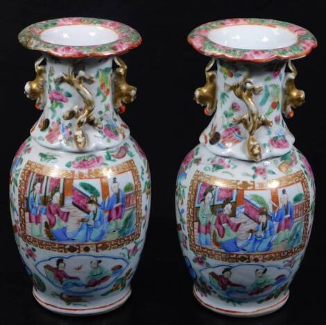 A pair of 19thC Cantonese famille rose vases, each with flared rims, floral stems and shouldered bodies, decorated with panels of figures surrounded by various flowers, predominately in pink, green, blue and turquoise, 23cm H. (2) (AF)