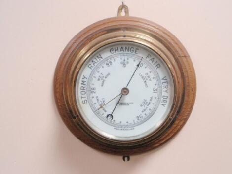 An oak and brass cased aneroid barometer marked John Barker & Co