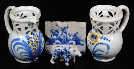 A pair of tin glazed Delft ware puzzle jugs, similarly designed, with pierced floral tops, single spouts, bulbous bodies, handpainted with flowers, predominately in yellow and blue, unmarked, 17cm H, a Dutch Delft figure of a standing bear, marked to the 